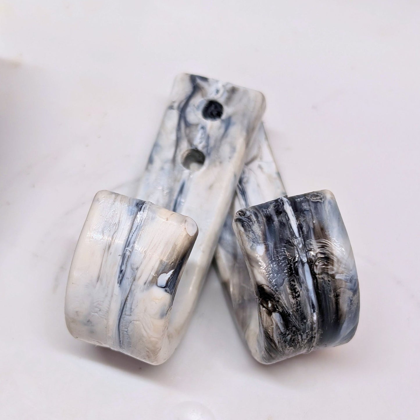 Two marble-patterned ceramic wall hooks on a white background