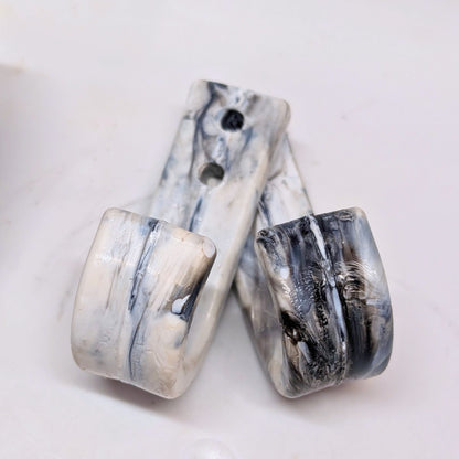 Two marble-patterned ceramic wall hooks on a white background
